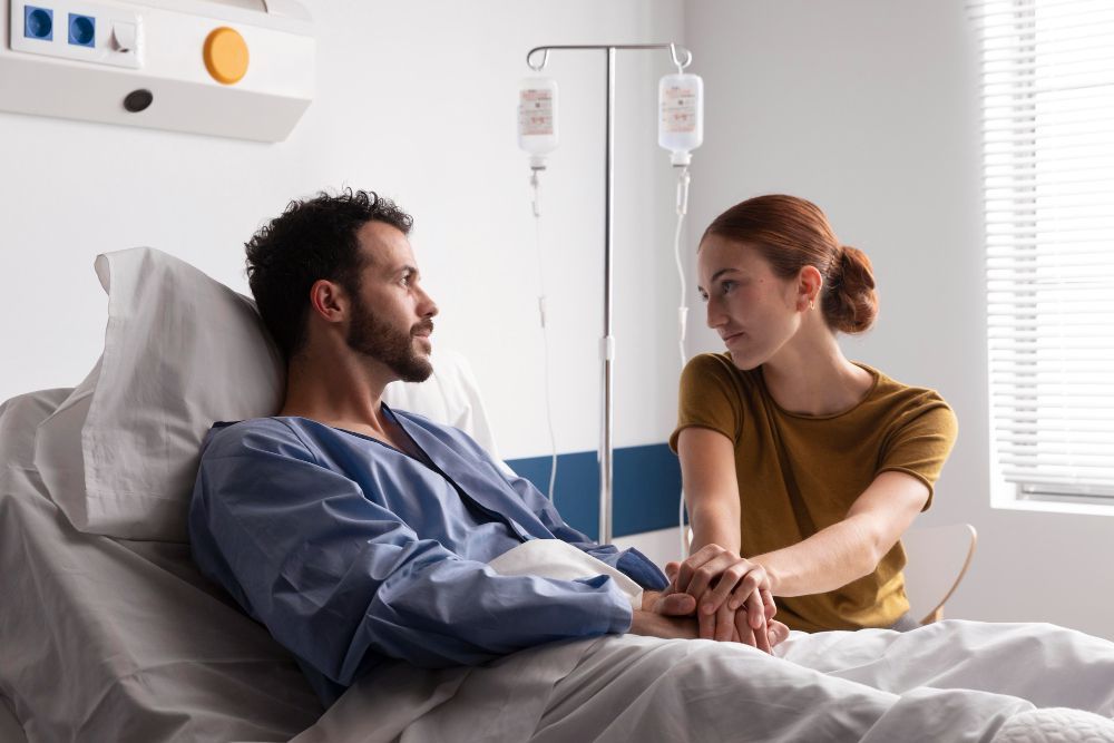 A woman is holding the hand of a man in a hospital bed.