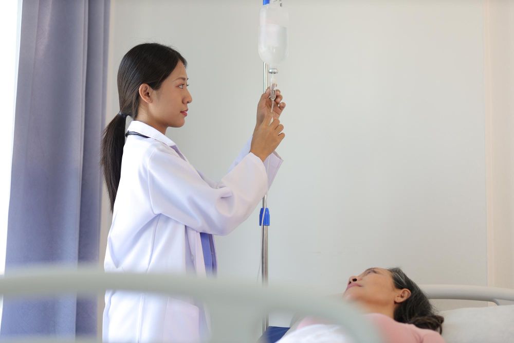 A doctor is giving an injection to a patient in a hospital bed.