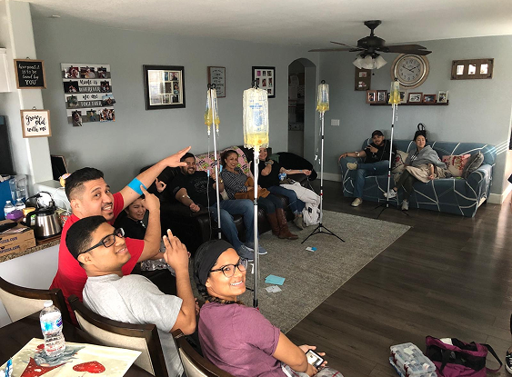 A group of people are sitting in a living room with iv drips.