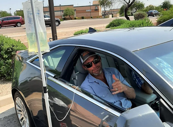 A man is giving a thumbs up while sitting in a car