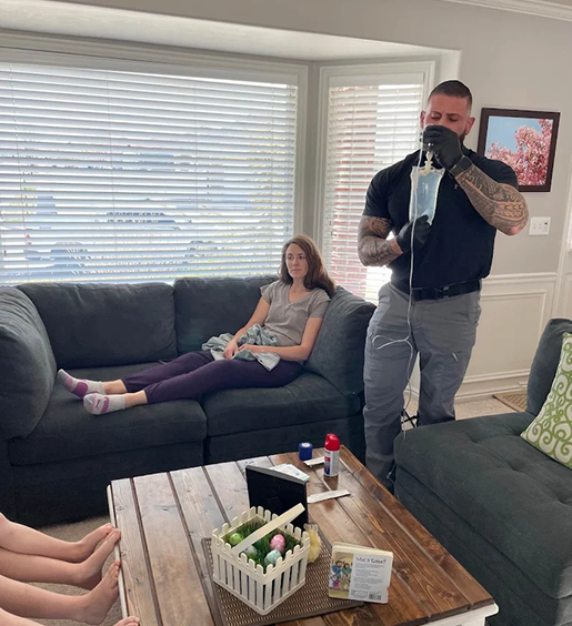 A man is standing next to a woman laying on a couch in a living room.