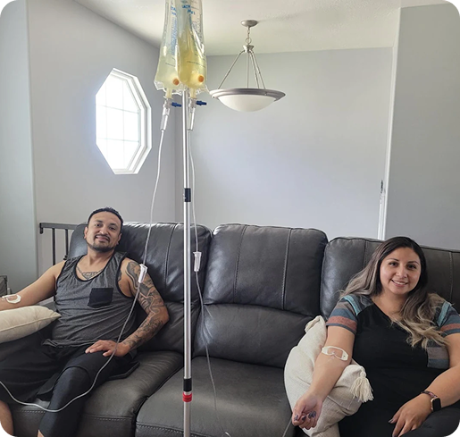 A man and a woman are sitting on a couch with an iv in their arm
