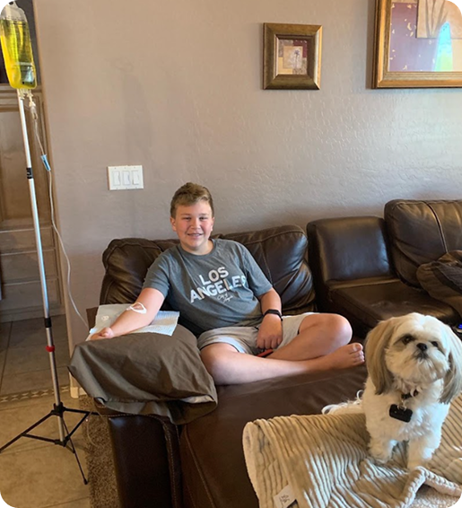 A boy in a los angeles shirt sits on a couch next to a dog