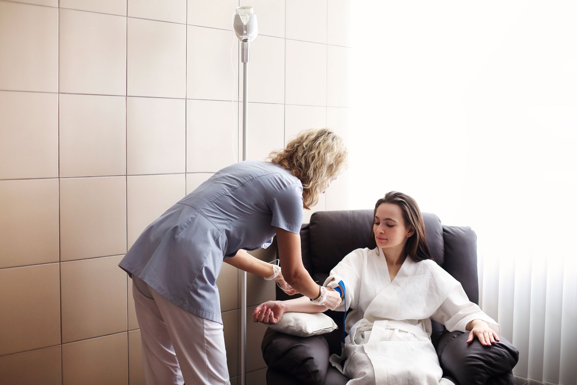 A woman is sitting in a chair getting an injection from a nurse.