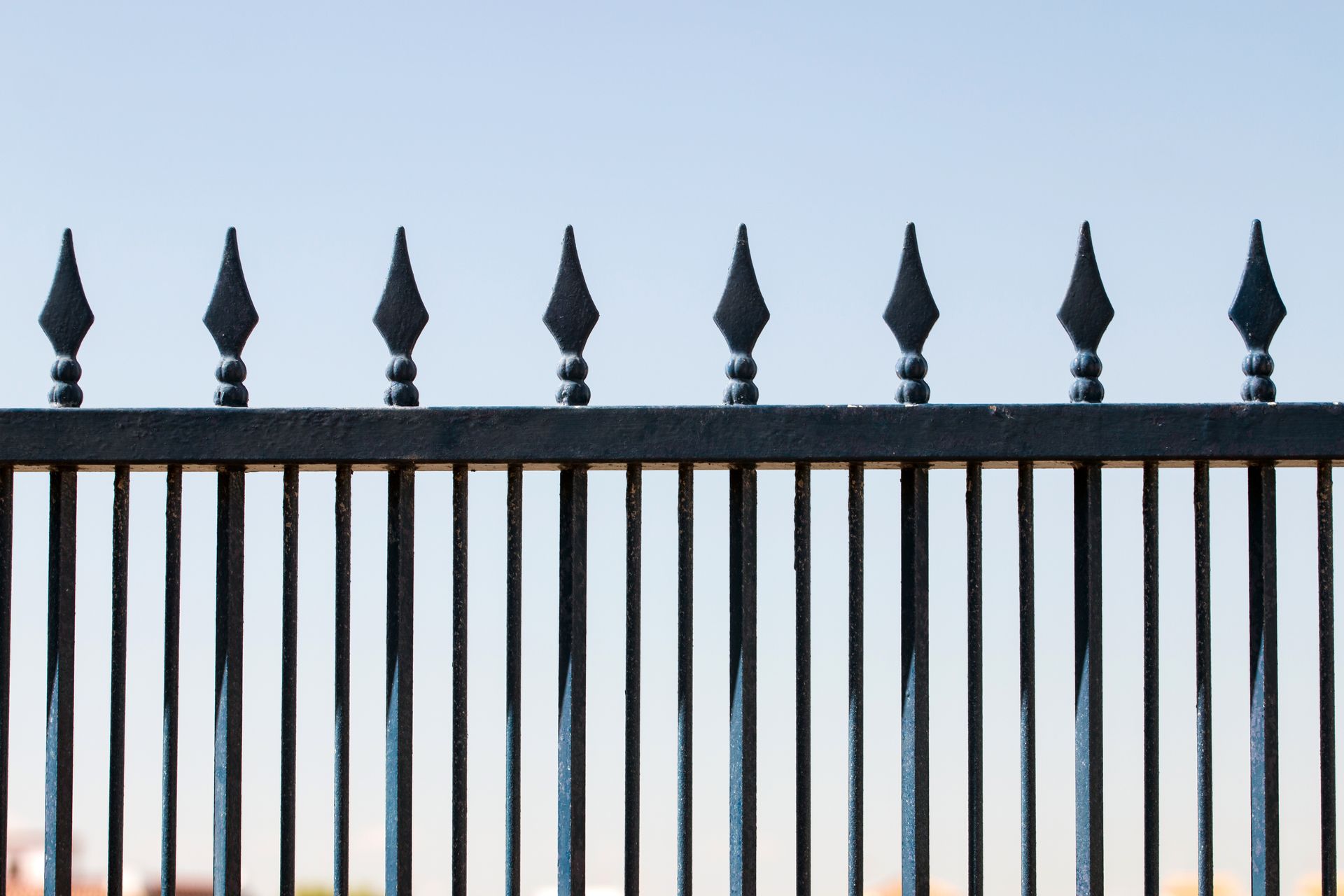 Iron forged fence silhouetted against a vibrant blue sky.