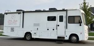 A white rv is parked in the driveway of a house.