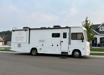 A white rv is parked on the side of the road in front of a house.