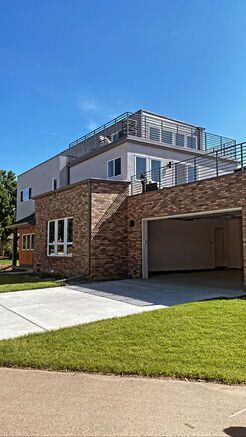 Modern two-story house with brick and stucco, garage, green lawn, blue sky.