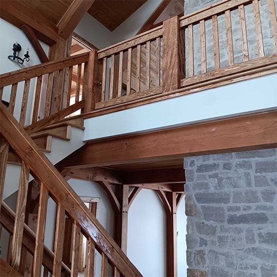 Wooden staircase and balcony with stone wall. Interior of a home with natural wood accents.
