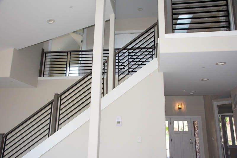 Modern staircase with black metal railings and white walls.
