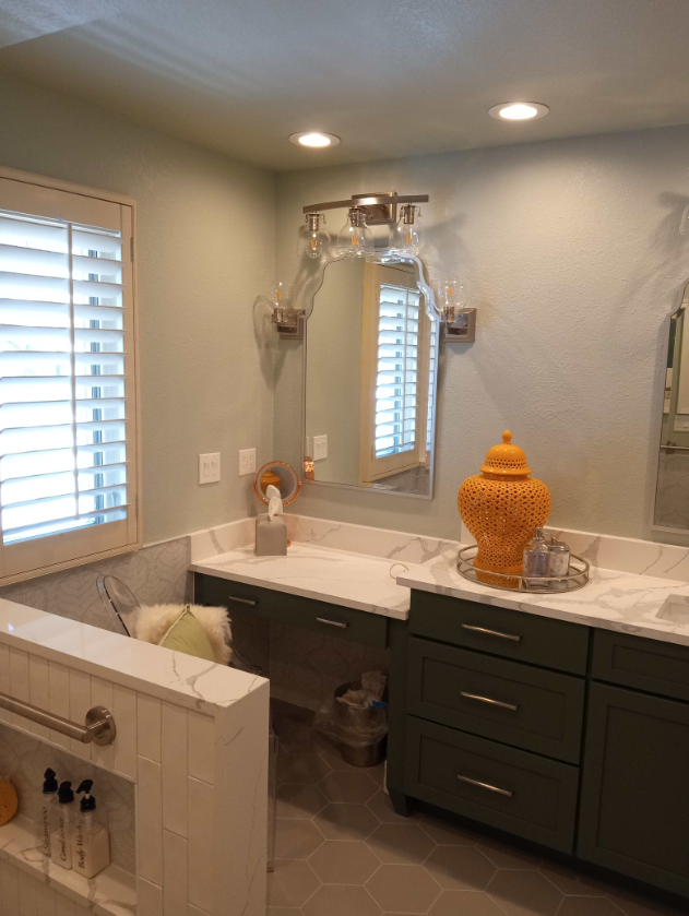 Bathroom with green cabinets, white countertops, shutters, and an orange decorative jar.