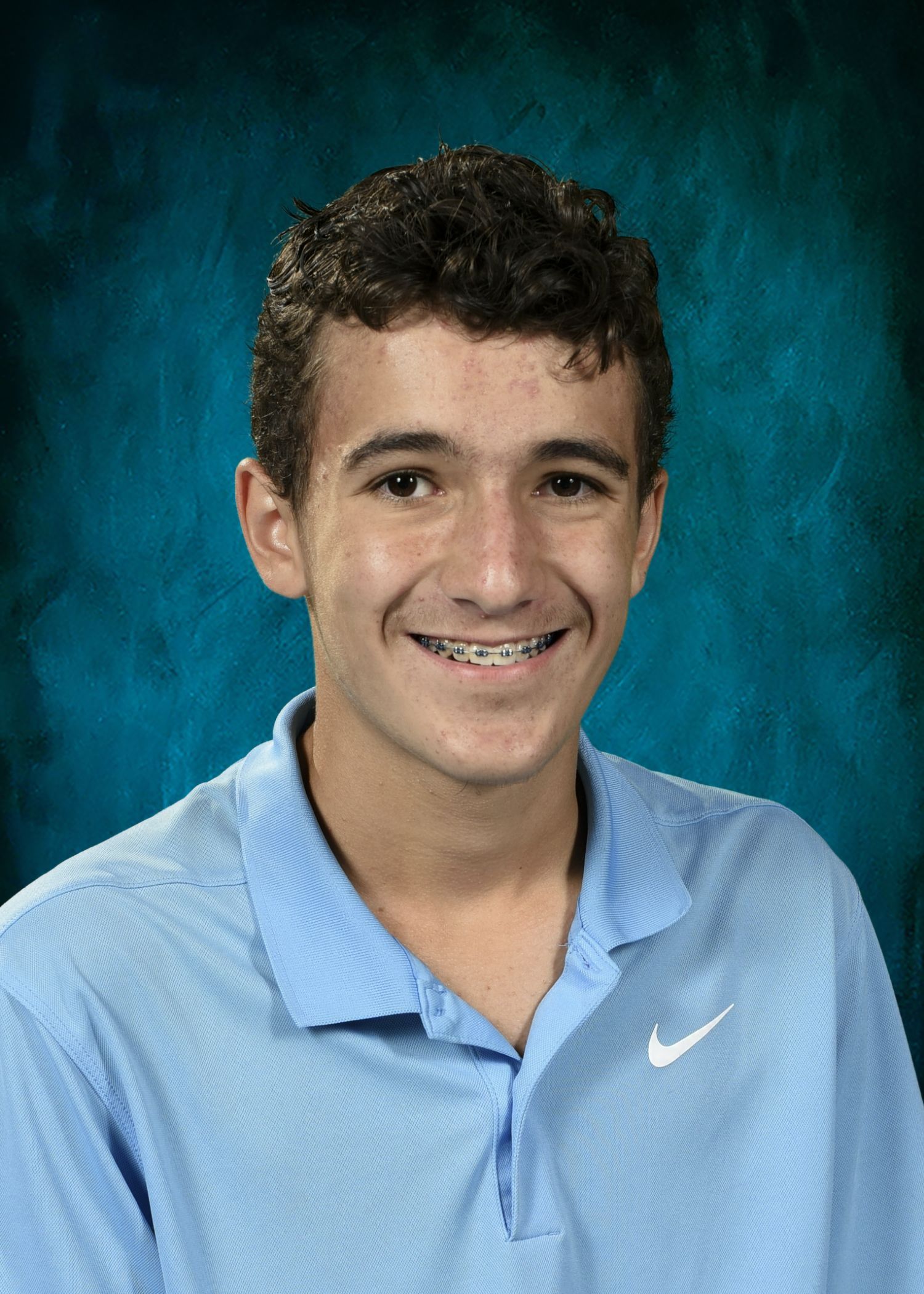 Boy with dark hair smiling, looking at the camera.