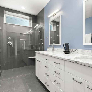 Modern bathroom with gray tiled shower, white vanity, and blue wall.