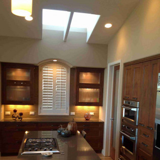 Kitchen with dark wood cabinets, skylights, and stainless steel appliances.