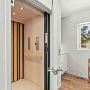 Interior residential elevator with tan walls and wooden accents.