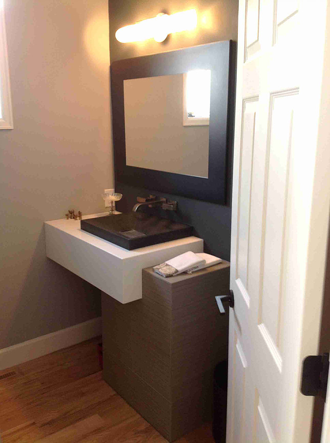 Modern bathroom with a floating sink, dark mirror, and gray walls next to a white door.