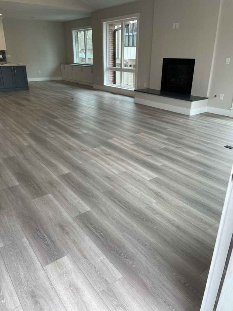 Light grey wood-look flooring in a living room with a fireplace and windows.