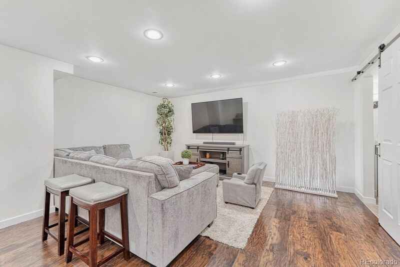 Living room with gray sectional sofa, TV, wooden floor, and white walls.
