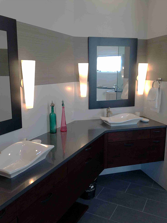 Modern bathroom with two sinks, dark wood cabinets, and white wall sconces.