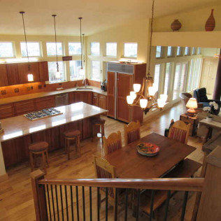 Spacious kitchen/dining area with wood cabinets, island, and table. Light from windows fills the room.