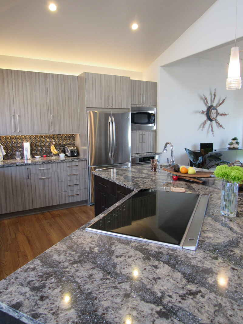 Modern kitchen with gray cabinets, granite countertops, and stainless steel appliances.