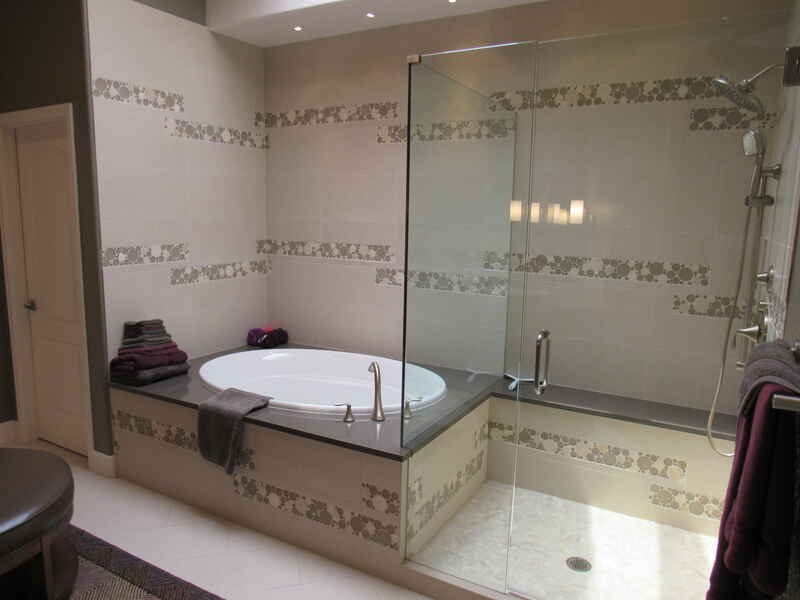 Modern bathroom with a tub, a glass shower, and light-colored tiles with mosaic accents.