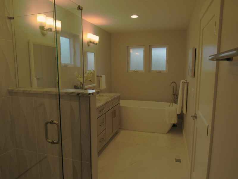 Modern bathroom with a glass shower, bathtub, double sink, and neutral colors.