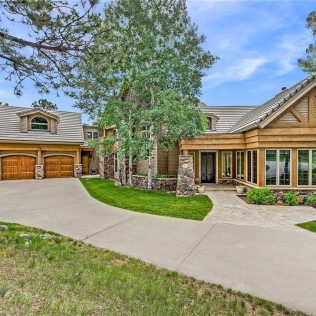 Upscale house with attached garage; stone and wood exterior; green lawn and driveway.