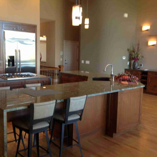 Spacious kitchen with island seating, wood cabinets, granite counters, and stainless steel appliances.