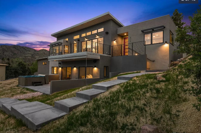 Modern two-story house at dusk with concrete steps leading up a grassy hill.