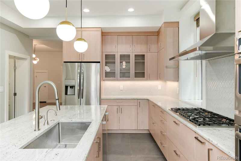 Modern kitchen with light wood cabinets, stainless steel appliances, and a large island.