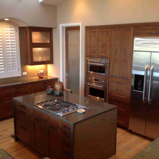 Kitchen with brown cabinets, stainless steel appliances, and a dark island with a gas stove.