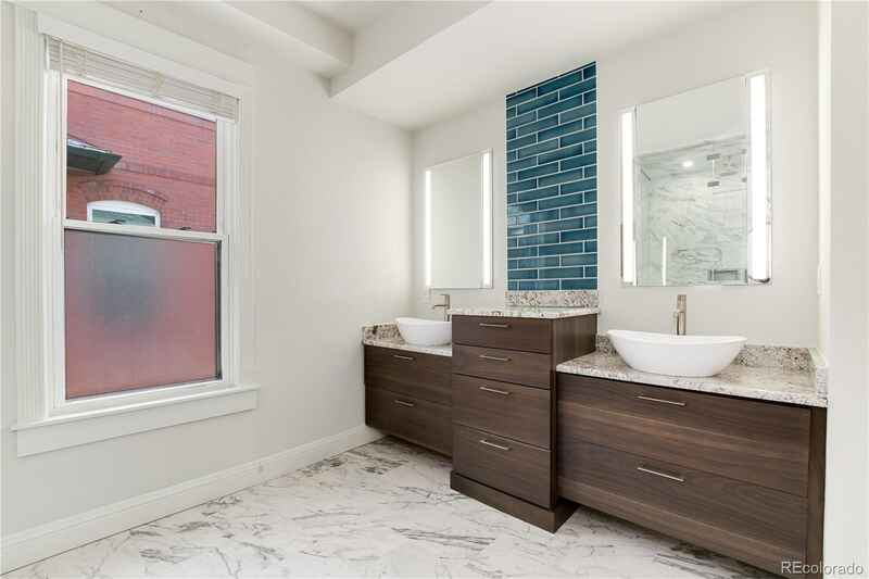 Modern bathroom with double vanity, marble floors, and teal tile accent wall.