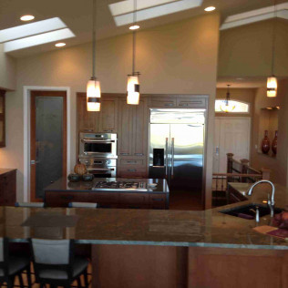 Kitchen with dark wood cabinets, stainless steel appliances, and pendant lights over a central island with a stovetop.