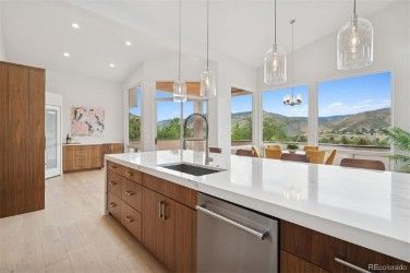 Spacious kitchen with wood cabinets, white countertops, and large windows overlooking a mountainous landscape.