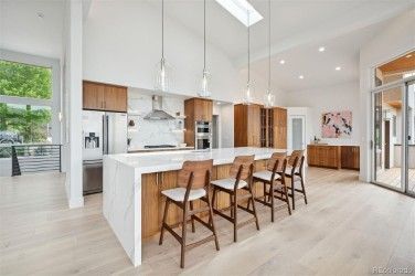Modern kitchen with wood cabinets, large white island, and bar stools.