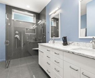 Modern bathroom with gray shower, blue walls, white vanity, and marble countertop.