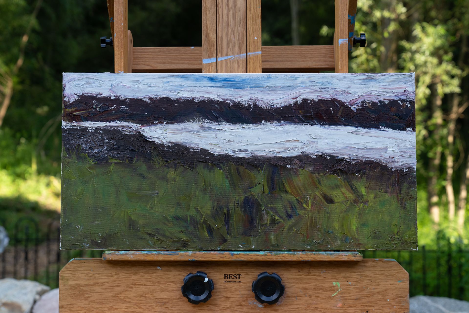 Painting on easel: abstract landscape, white horizontal stripe, green and brown fields, blue sky.