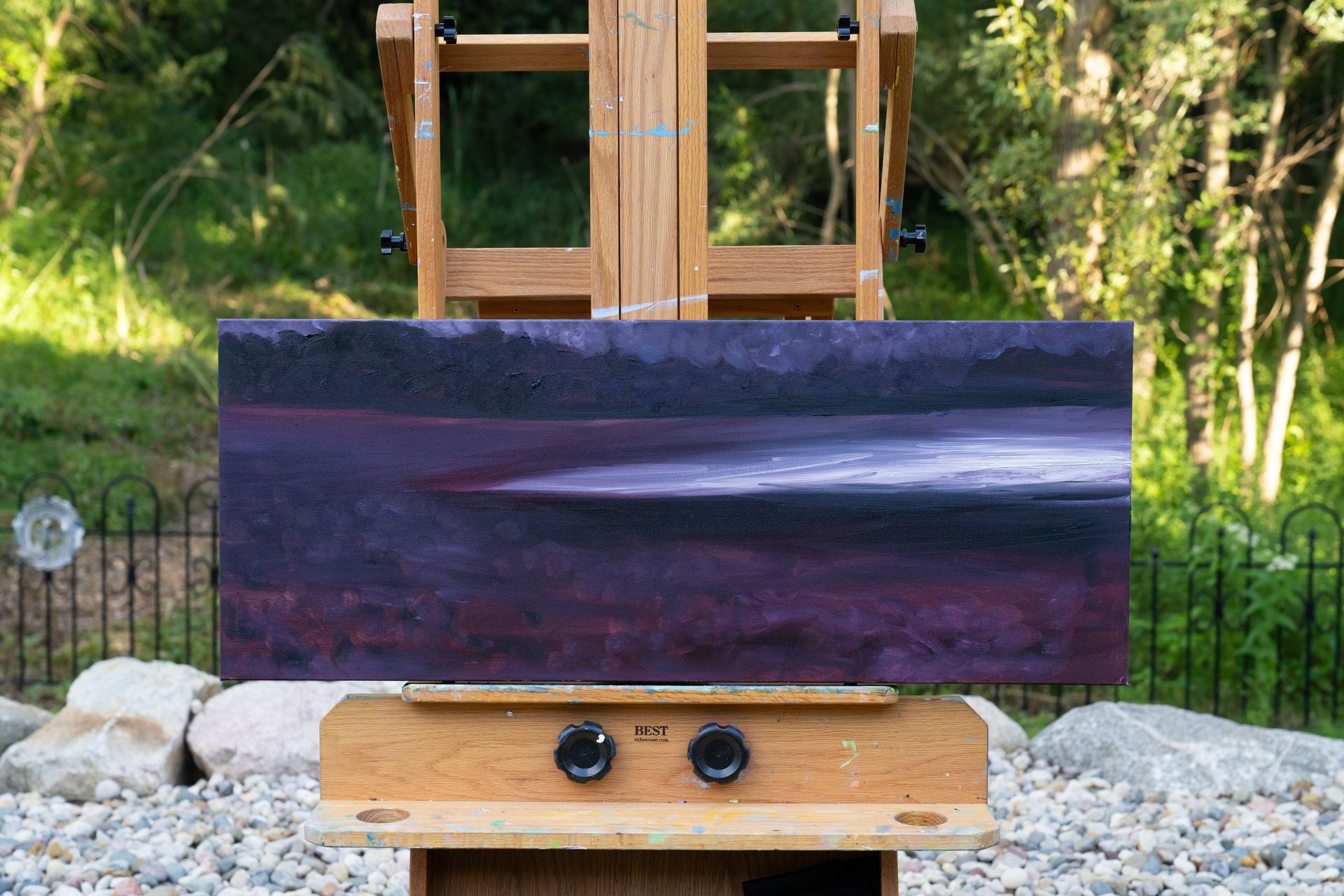Painting on an easel outdoors. Landscape in shades of purple and white.