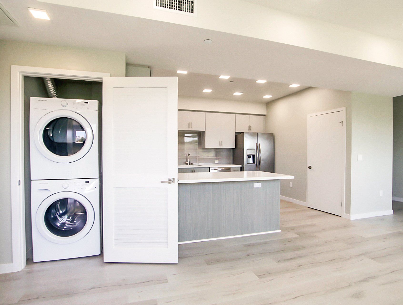 Interior of apartment with grey flooring and stackable washer and dryer.