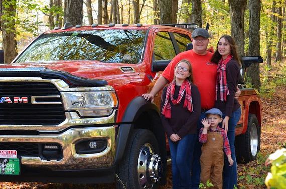 A family is posing for a picture in front of a red truck.