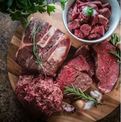 A wooden cutting board topped with meat and a bowl of meat.