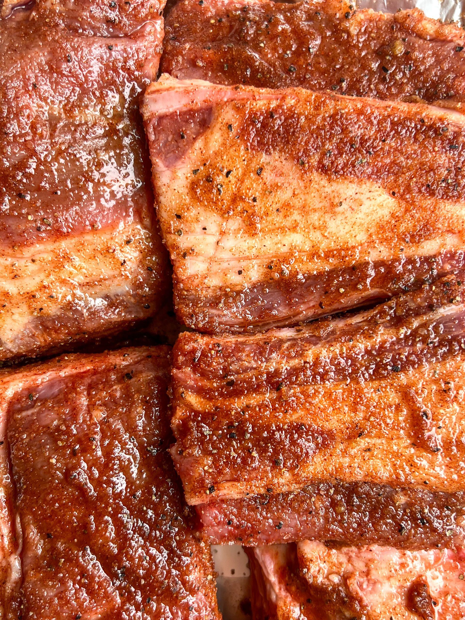 A close up of a pile of ribs with sauce on them.