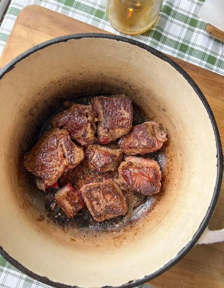 A bowl of meat is cooking in a pot on a table.