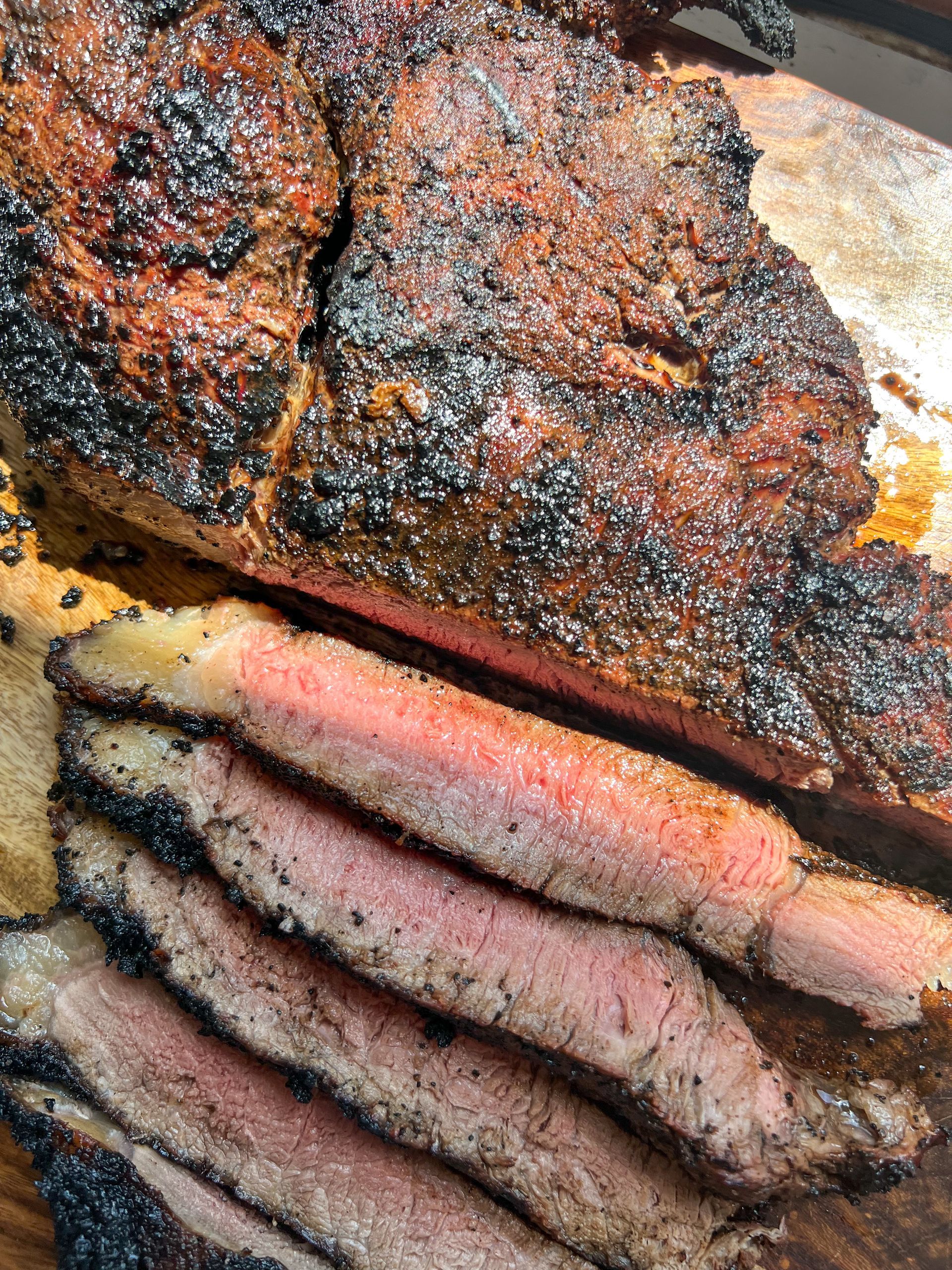 A large piece of meat is sitting on top of a wooden cutting board.
