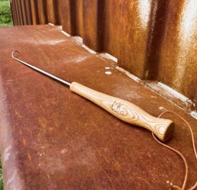 A wooden hook is sitting on a rusty surface.
