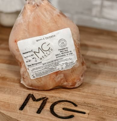 A bag of chicken is sitting on a wooden cutting board.