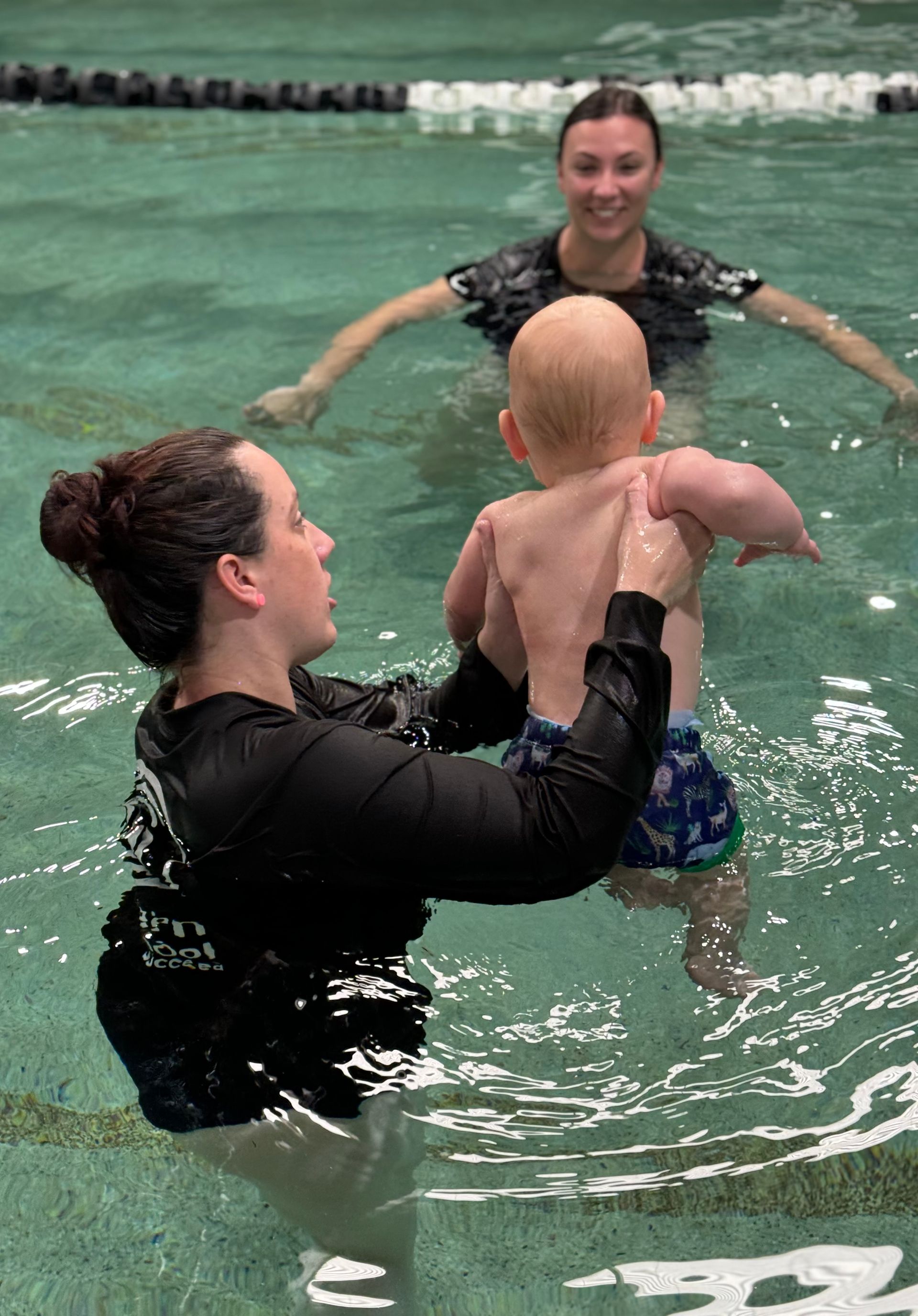 A woman is holding a baby in a swimming pool.