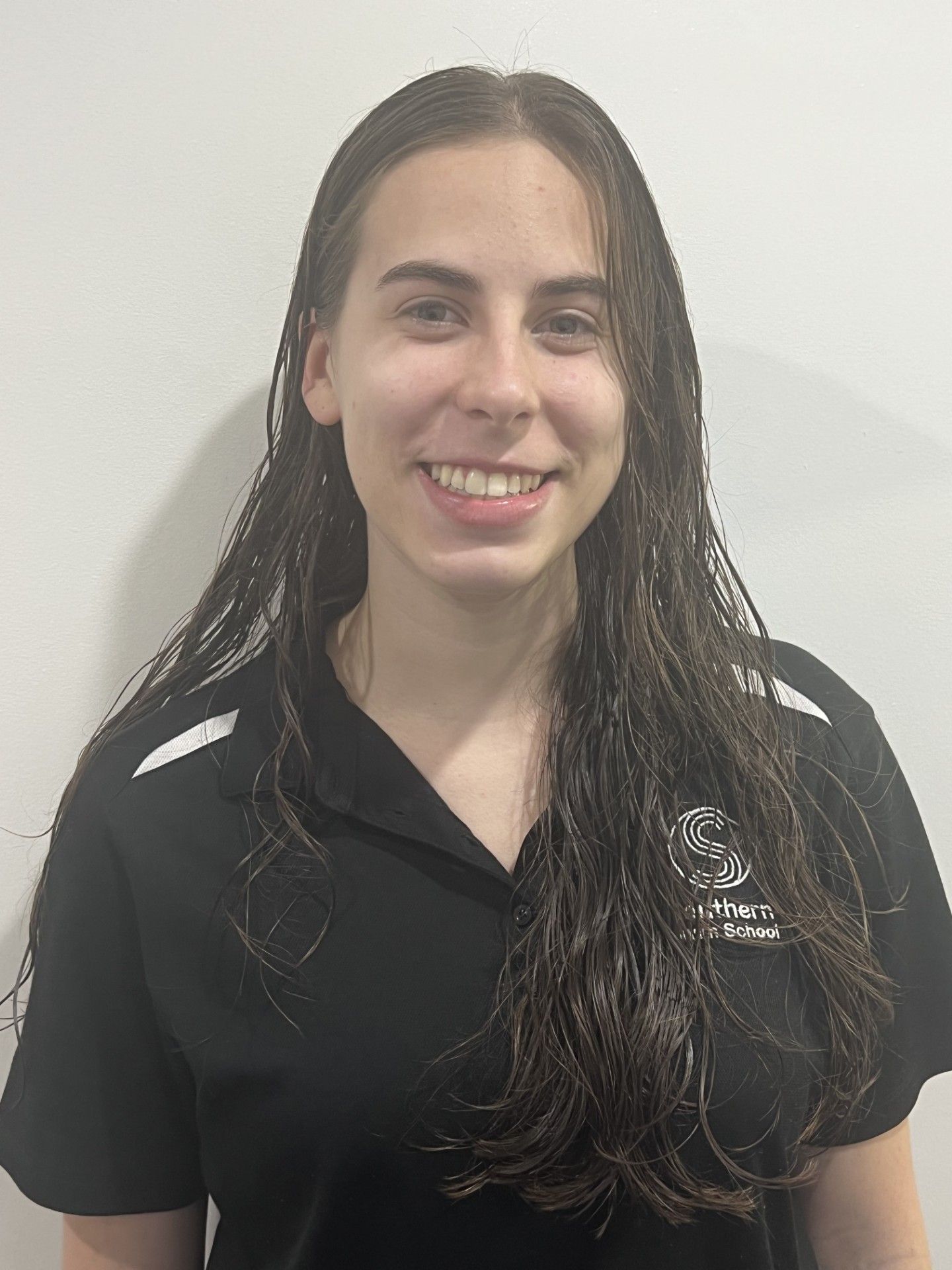 A woman with long hair is wearing a black shirt and smiling.