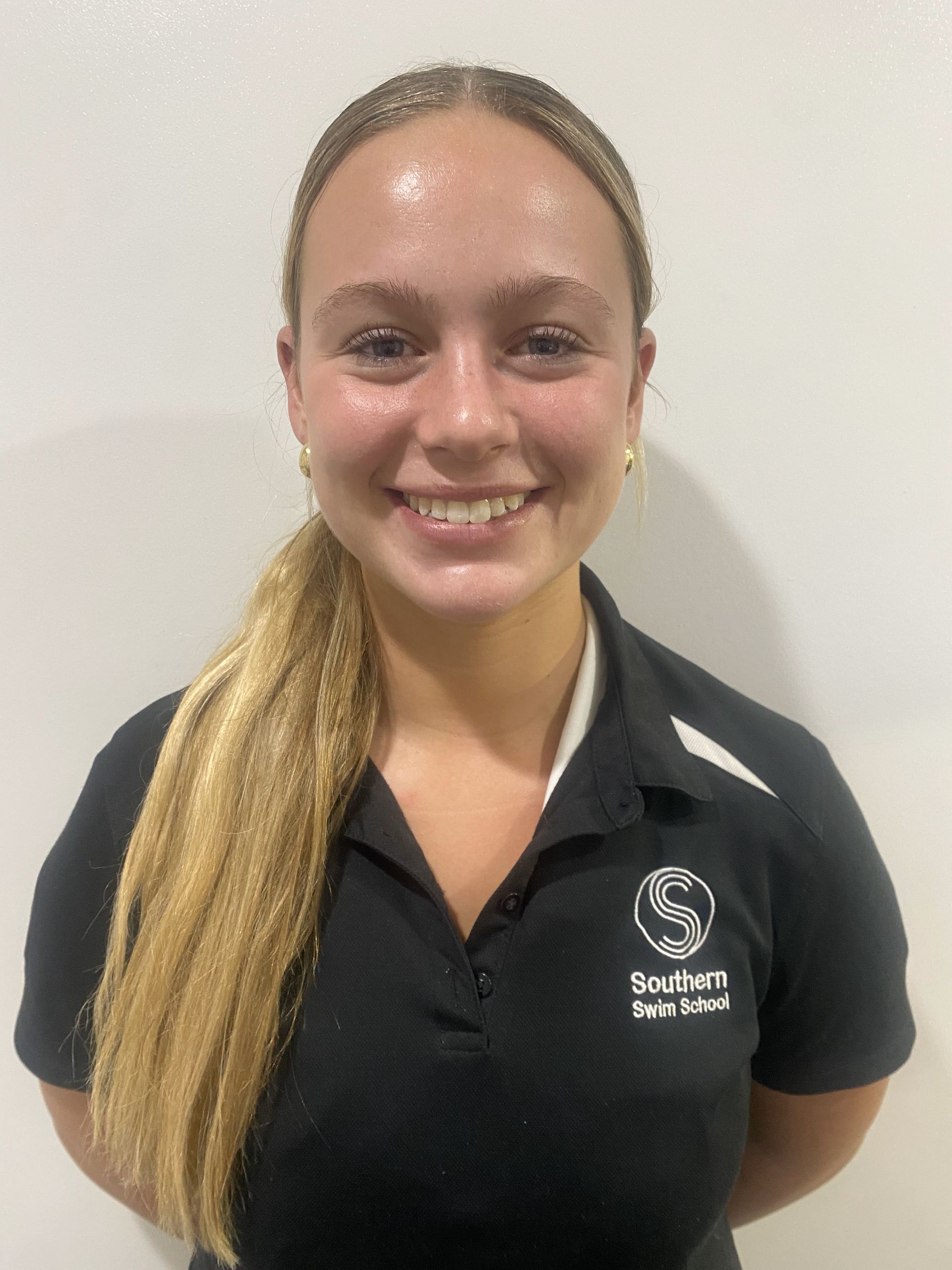 A young woman wearing a black polo shirt is smiling for the camera.